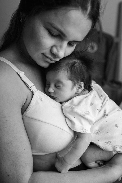 Free A serene black and white portrait of a mother gently holding her sleeping baby. Stock Photo