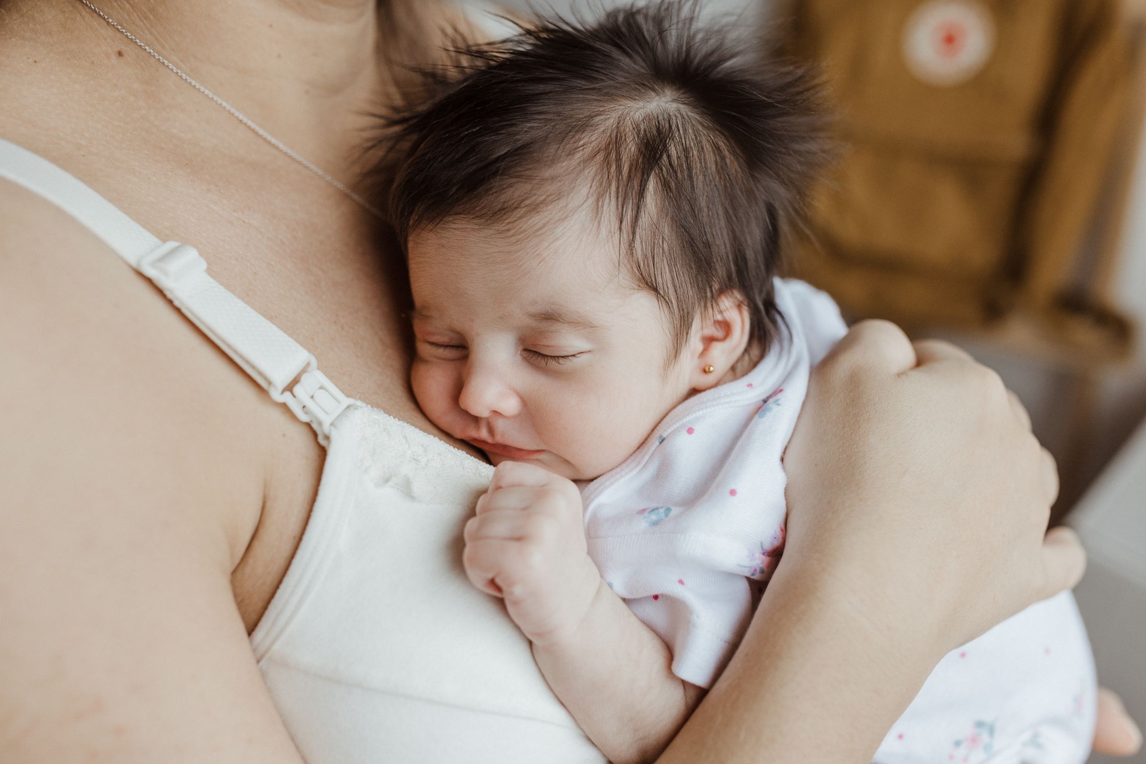 Mãe exausta abraçando seu bebê recém-nascido, simbolizando a complexidade emocional e a ansiedade no pós-parto