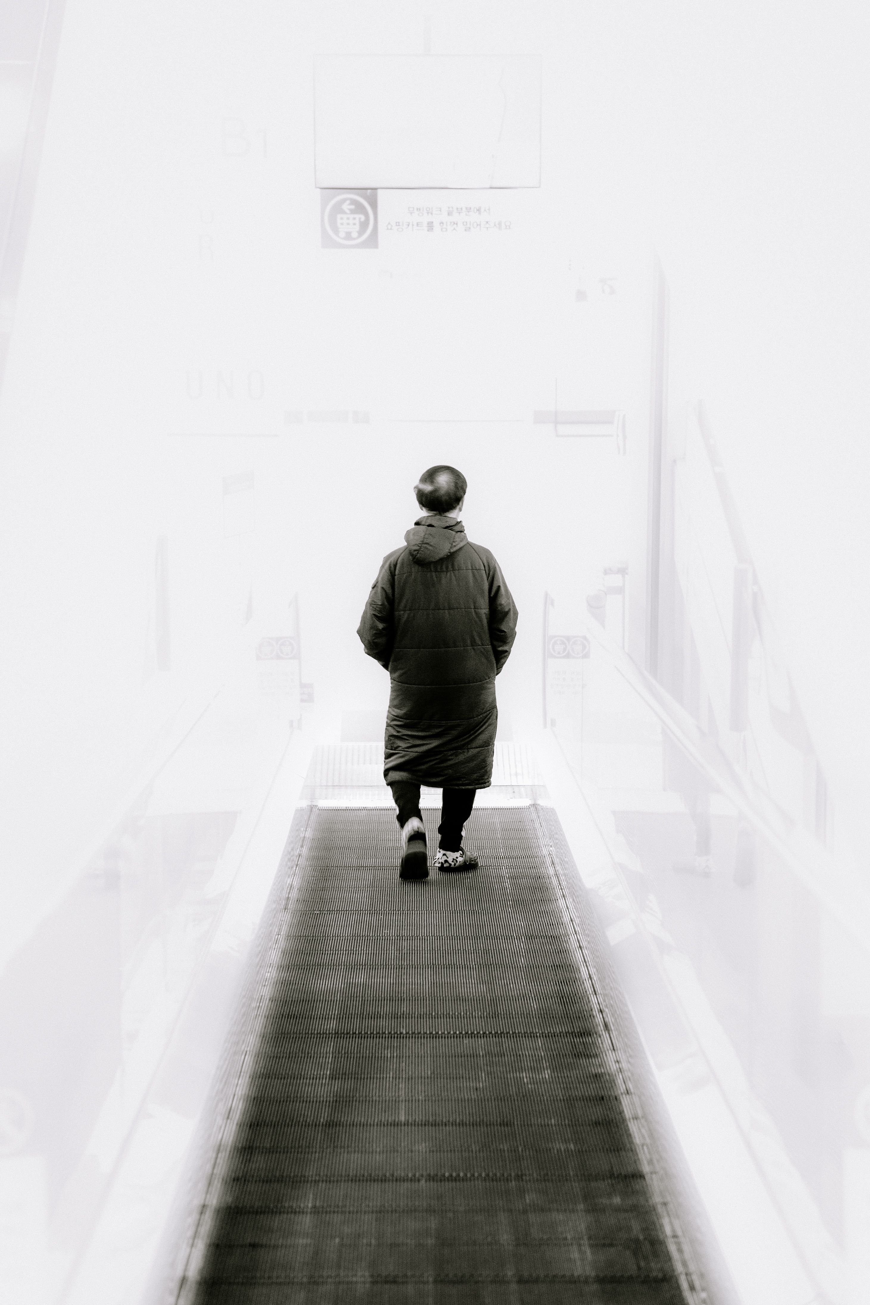 A solitary person walks down a high-key minimalist corridor, hands in pockets.. solitary, person, walks