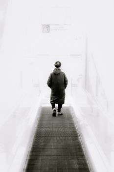 A solitary person walks down a high-key minimalist corridor, hands in pockets.. solitary, person, walks