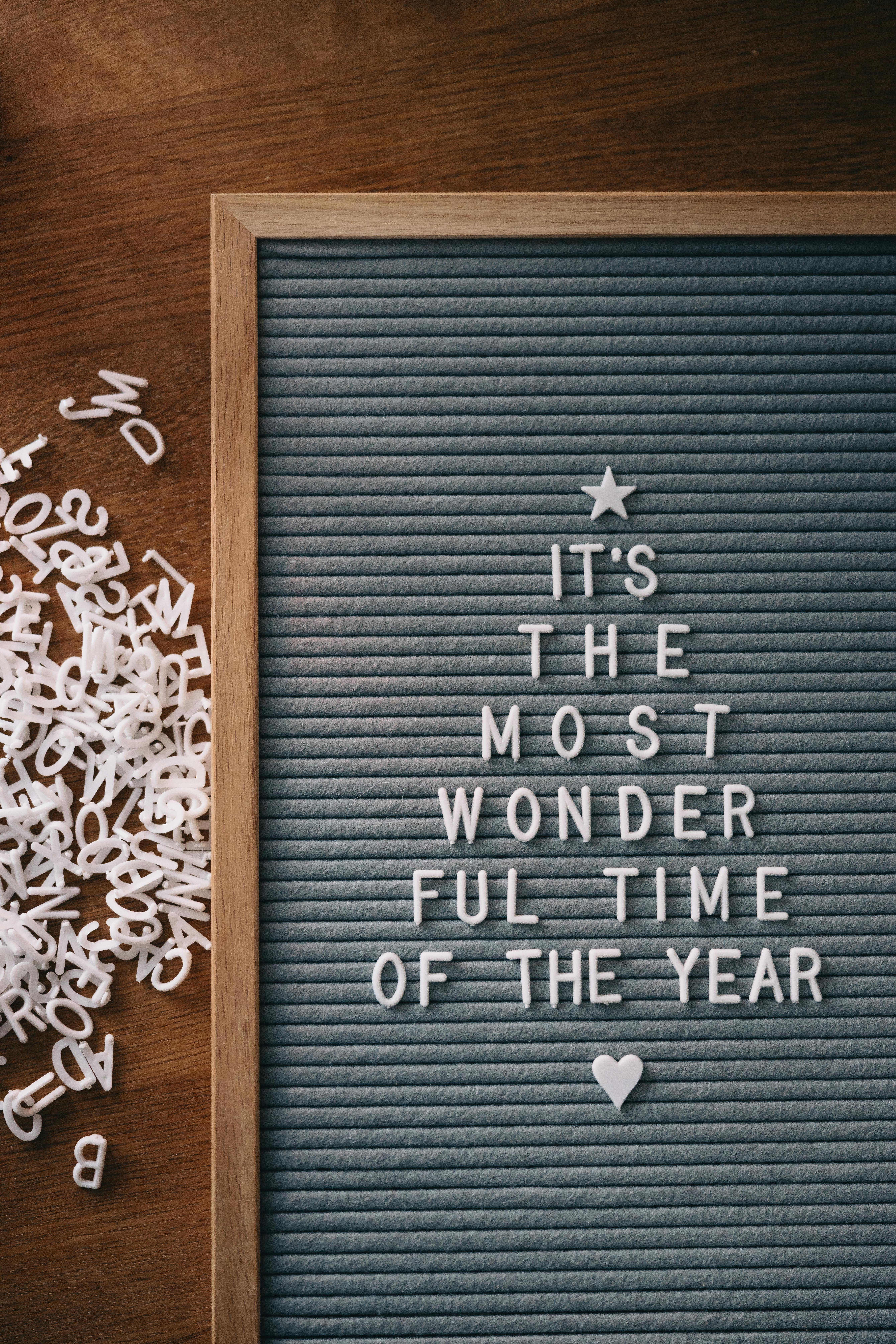 A letter board with Christmas message shaped like a tree on wooden background.