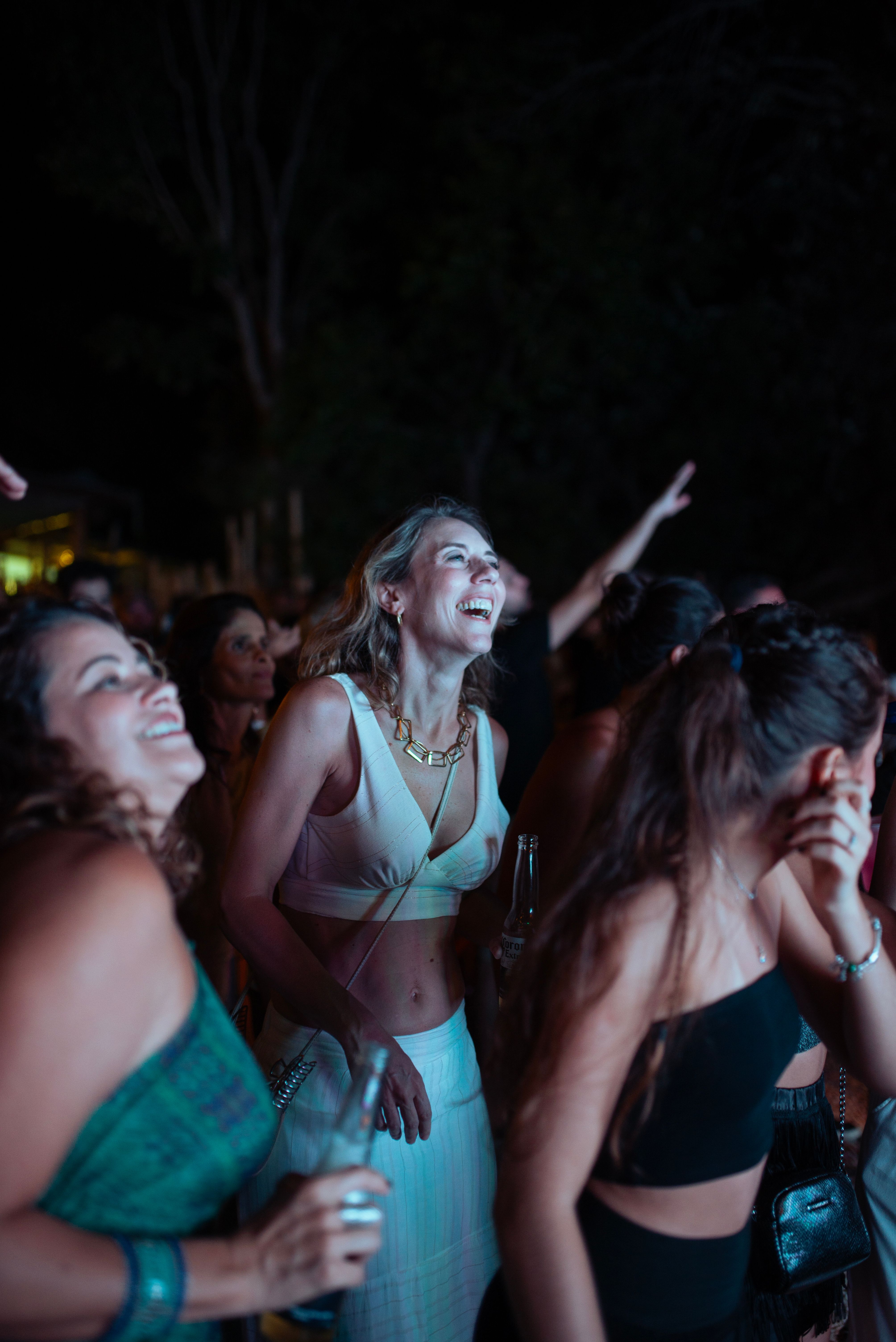 A group of women enjoying an energetic concert at night, surrounded by lively atmosphere.