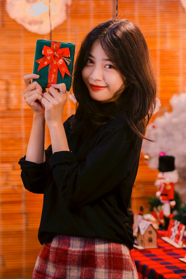 Young Woman Holding A Christmas Present And Smiling