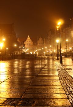 Beautifully lit old town square with historic tenements and street lamps at night.