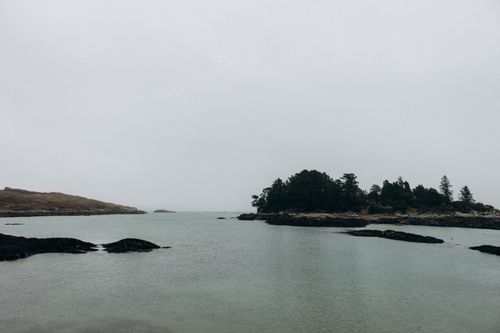Free A tranquil coastal view featuring misty forested islands and calm waters. Stock Photo