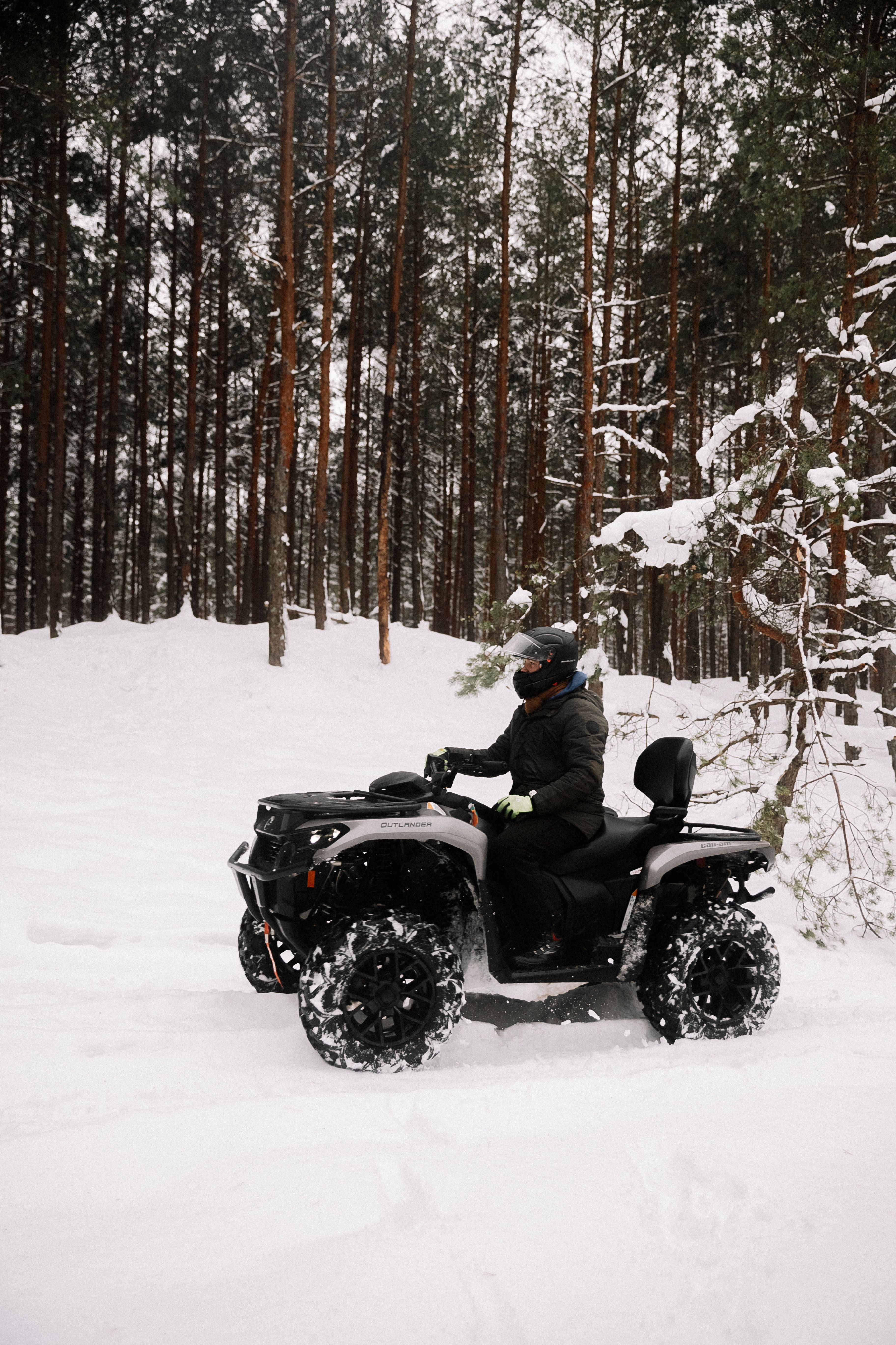 Rider navigating a snowy forest on an ATV, showcasing winter outdoor adventure.