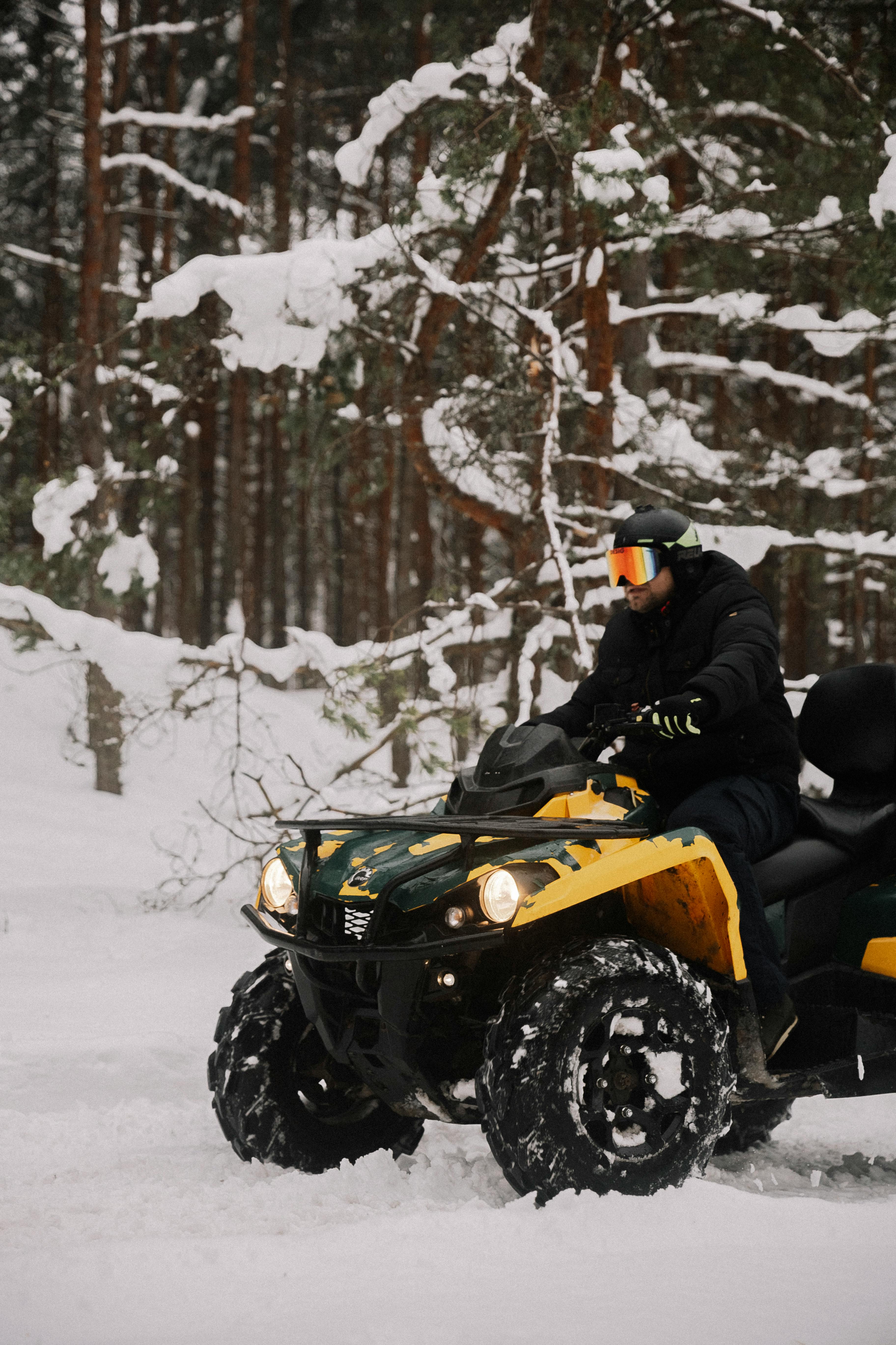 Winter scene of an ATV rider navigating snowy forest trails.