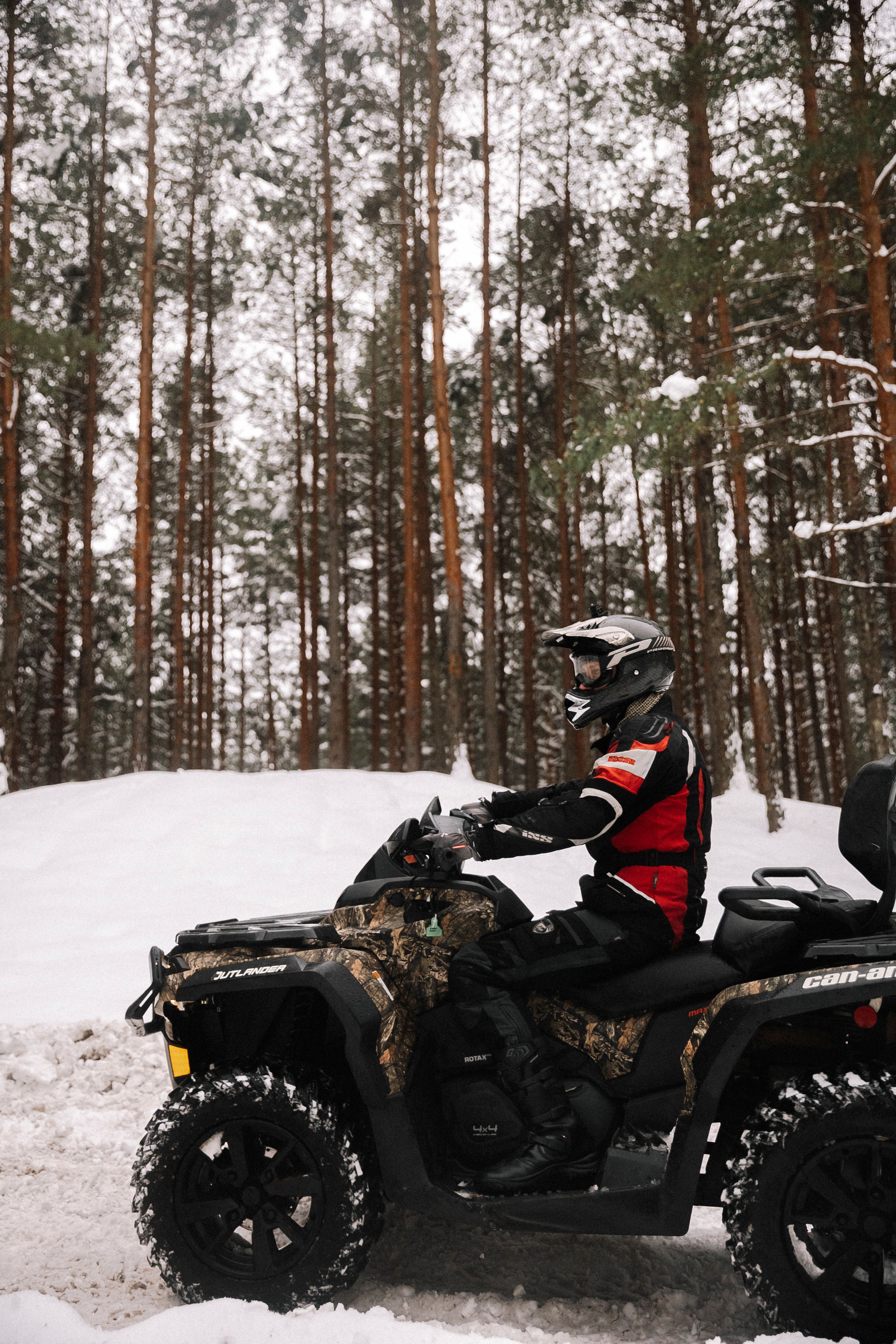 Person riding an ATV in a snowy forest landscape, capturing winter adventure.