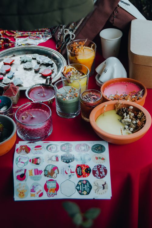 Free Vibrant collection of handmade candles and decorative stickers on a red tablecloth. Stock Photo