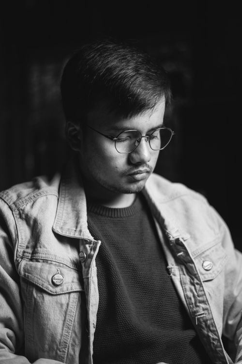 Free Black and white portrait of a man in eyeglasses and a jean jacket, deep in thought. Stock Photo