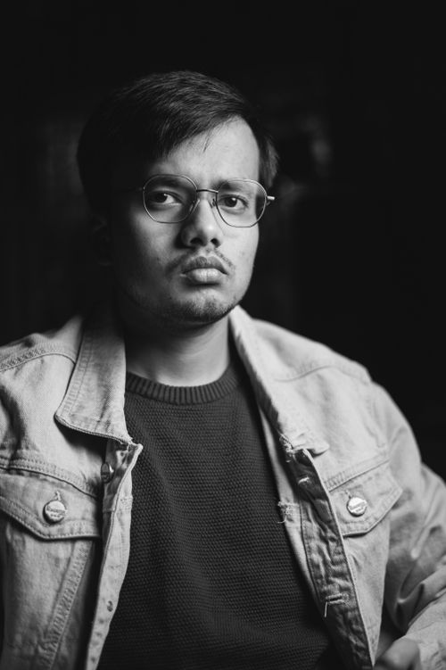 Free Moody black and white portrait of a young man with eyeglasses in a jean jacket. Stock Photo