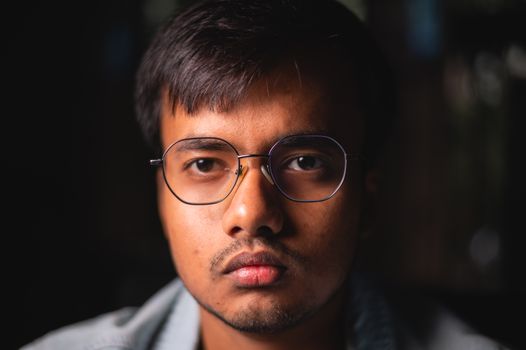 Intense close-up portrait of a man wearing eyeglasses with a serious expression.