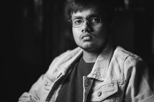 Free Moody black and white portrait of a man wearing glasses and a jean jacket. Stock Photo