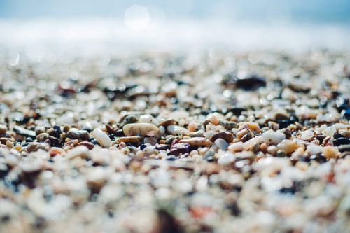 Free A detailed close-up of colorful pebbles on a beach with a beautiful bokeh effect in the background. Stock Photo