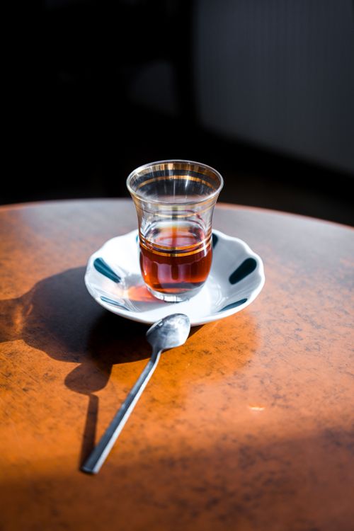 Free Turkish tea served in a traditional glass on a sunlit table, creating a cozy cafe ambiance. Stock Photo