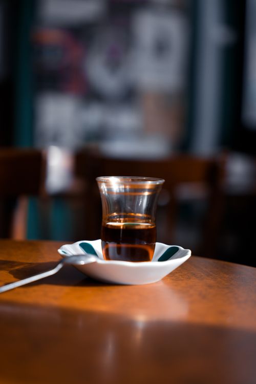Free Warm Turkish tea served in a traditional glass with saucer on a cafe table. Stock Photo