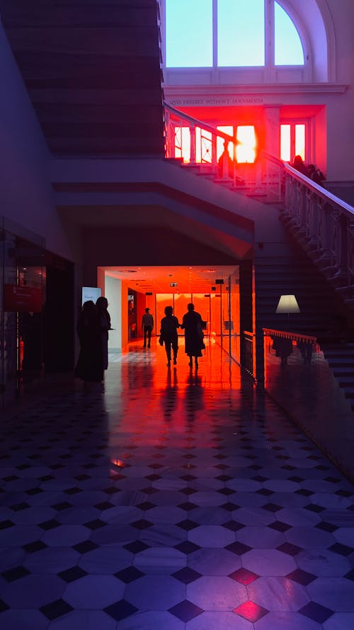 Silhouettes of People Walking into Passageway Illuminated Red