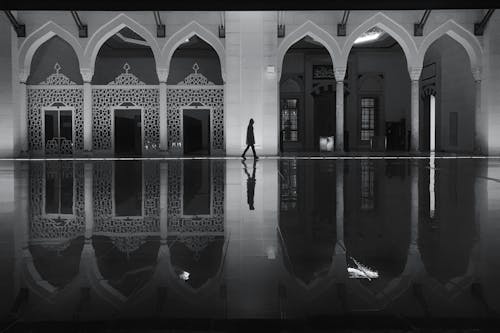 Silhouette of Man Walking in Front of a Mosque in Black and White 