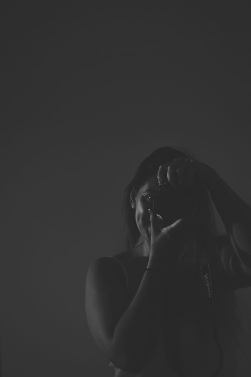 Free Elegant black and white studio portrait of a woman photographer capturing the moment. Stock Photo