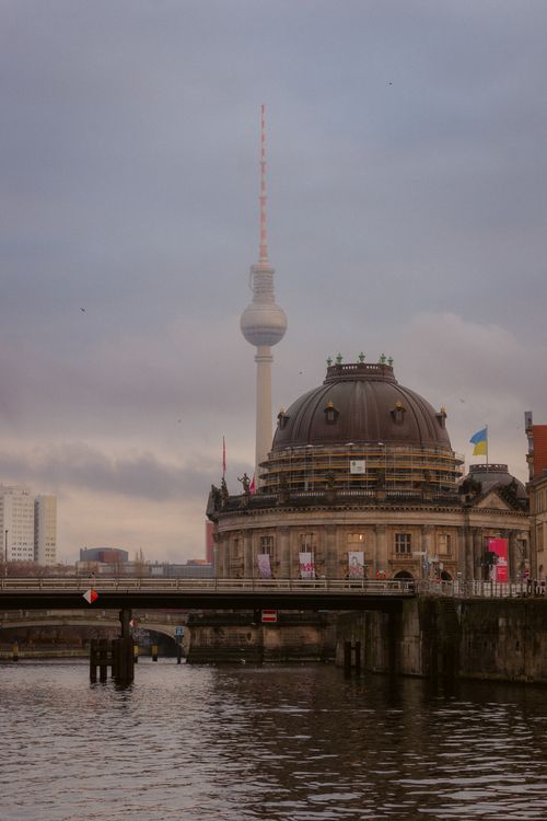 Free View of Berlin's Fernsehturm and historic building along the river on a cloudy day. Stock Photo