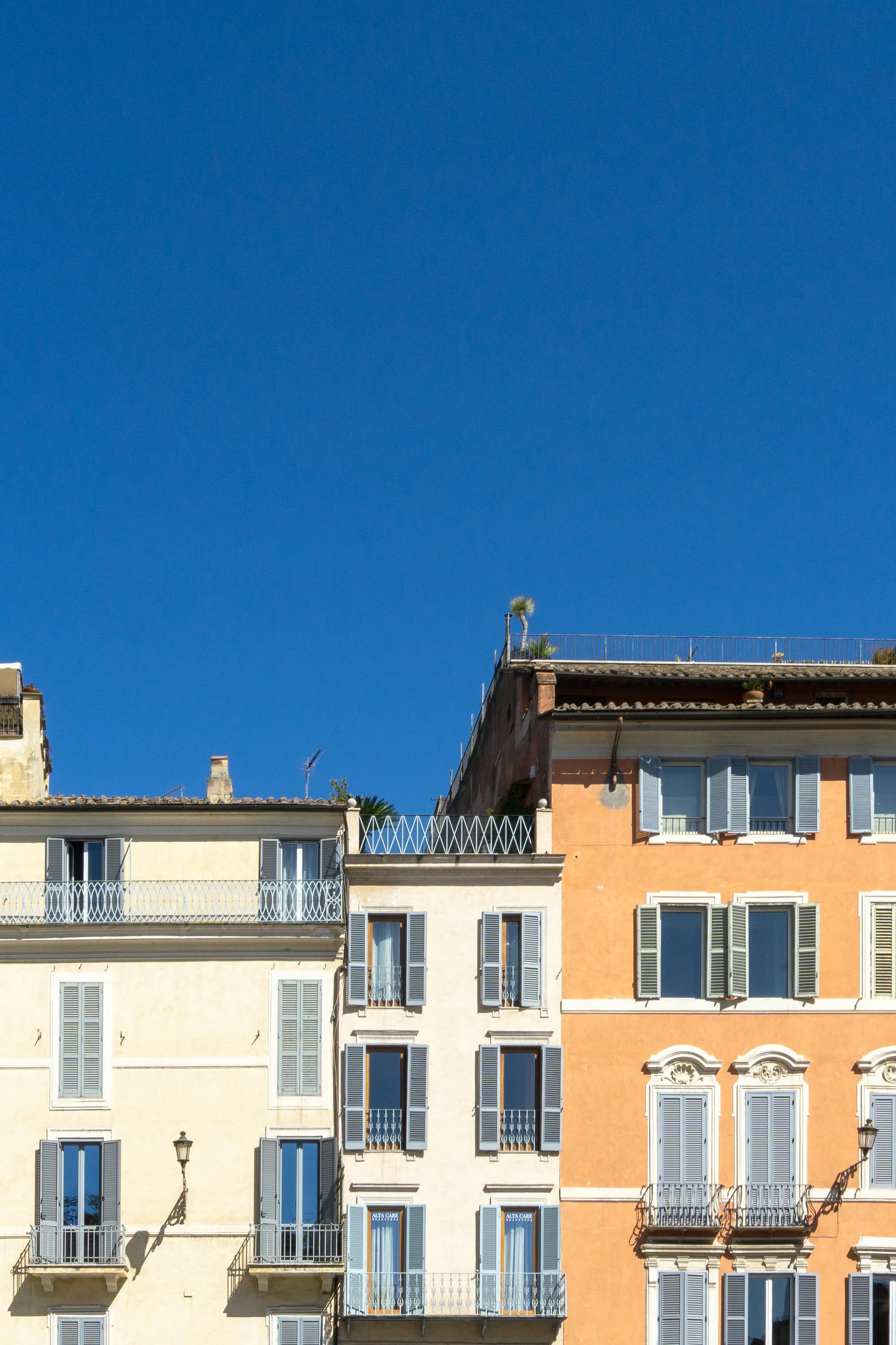 Vibrant Roman apartment buildings with classic facades and windows under a clear blue sky, in Rome, Italy.