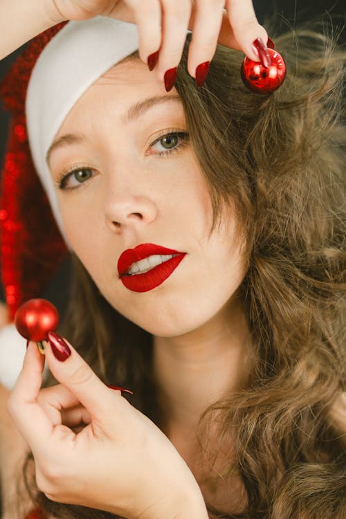 Portrait of a Woman Wearing a Santa Hat Holding Small Christmas Baubles