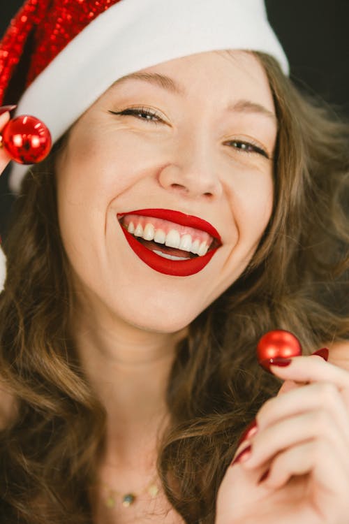 Smiling Model in Santa Hat Holding Christmas Baubles