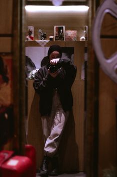 Woman photographing her reflection with a digital camera indoors.
