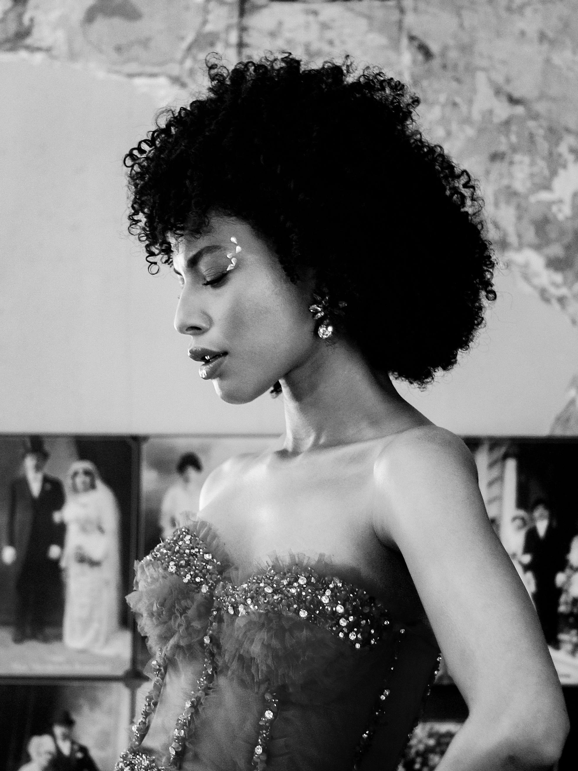 Stylish black and white portrait of a model with curly hair, wearing a strapless dress.