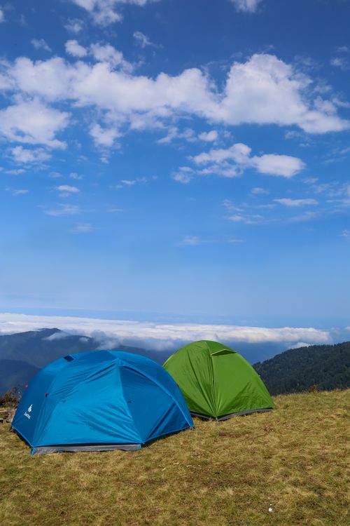 Free Two colorful tents on a grassy mountain peak under a clear blue sky. Stock Photo