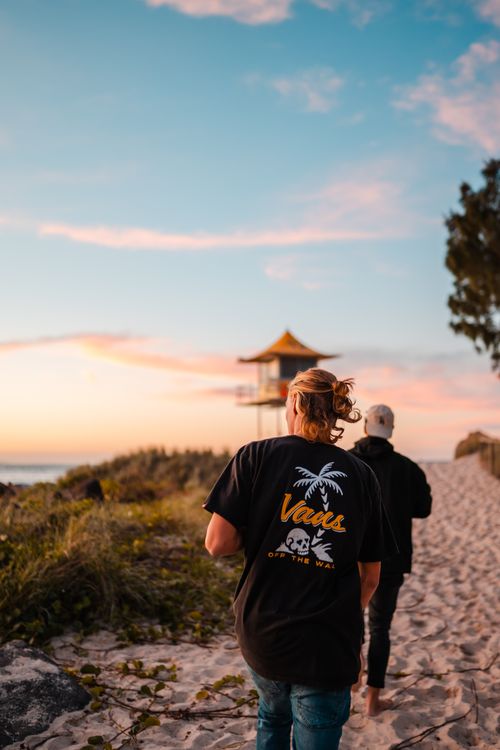 Free Two friends enjoy a leisurely walk on a sandy beach at sunset on the Gold Coast, Australia. Stock Photo
