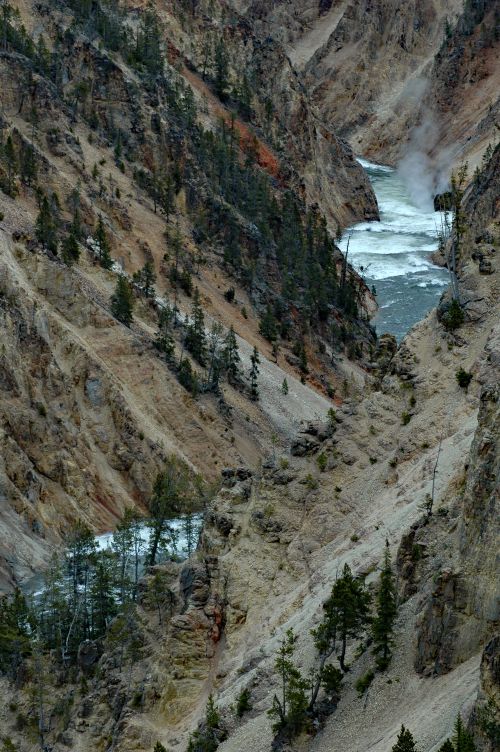 Free A dramatic aerial view of a rugged canyon with a flowing river and dense trees. Stock Photo