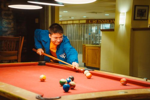 Free A focused young man aims at a pool table in a modern indoor recreation area. Stock Photo