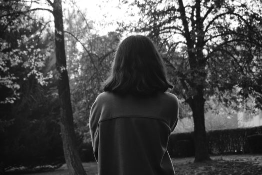 Black and white photo of a woman in a forest, backlit by soft sunlight.