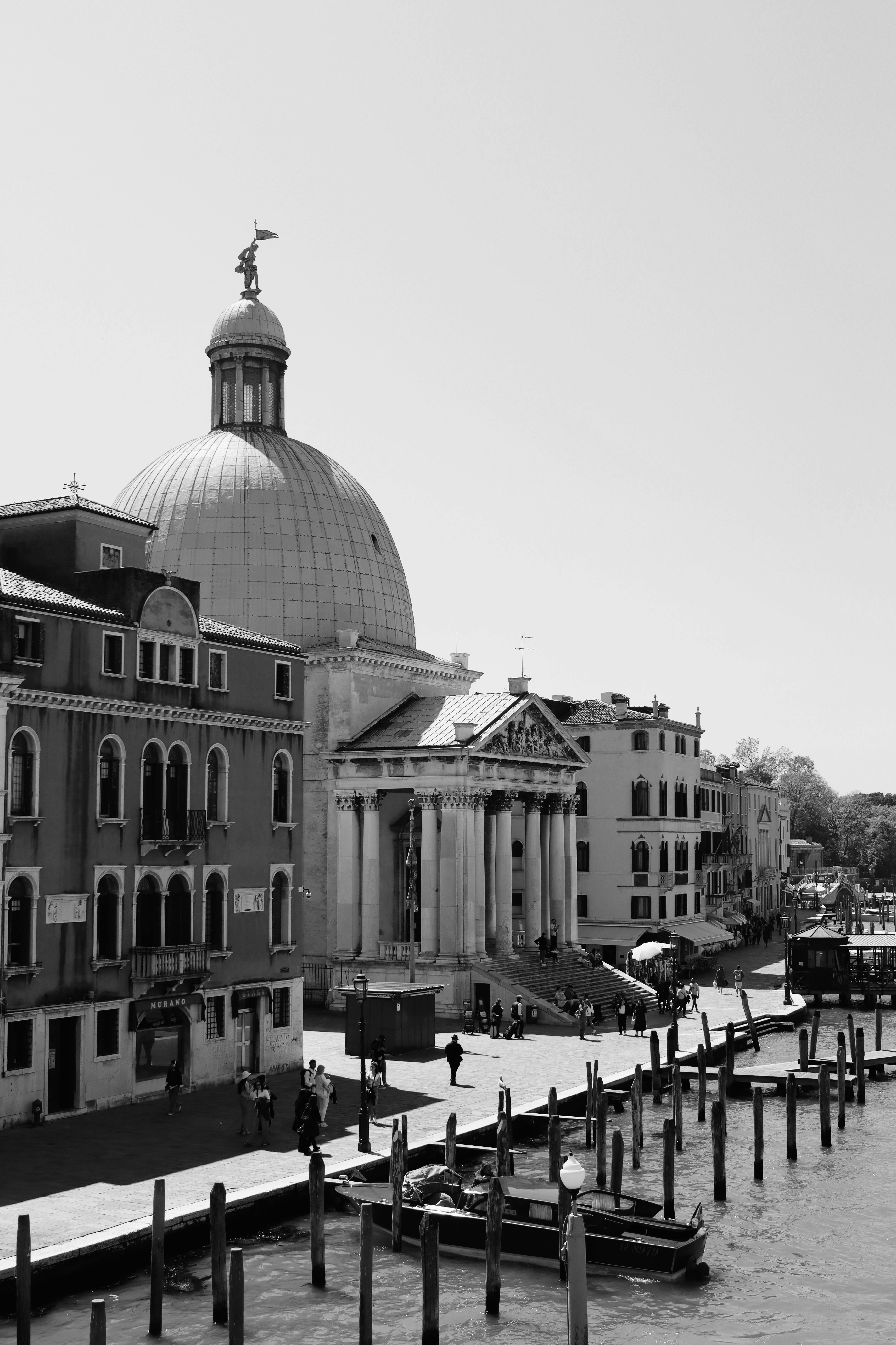 Black and white photo of Venice's historic waterfront architecture with gondolas along the canal.