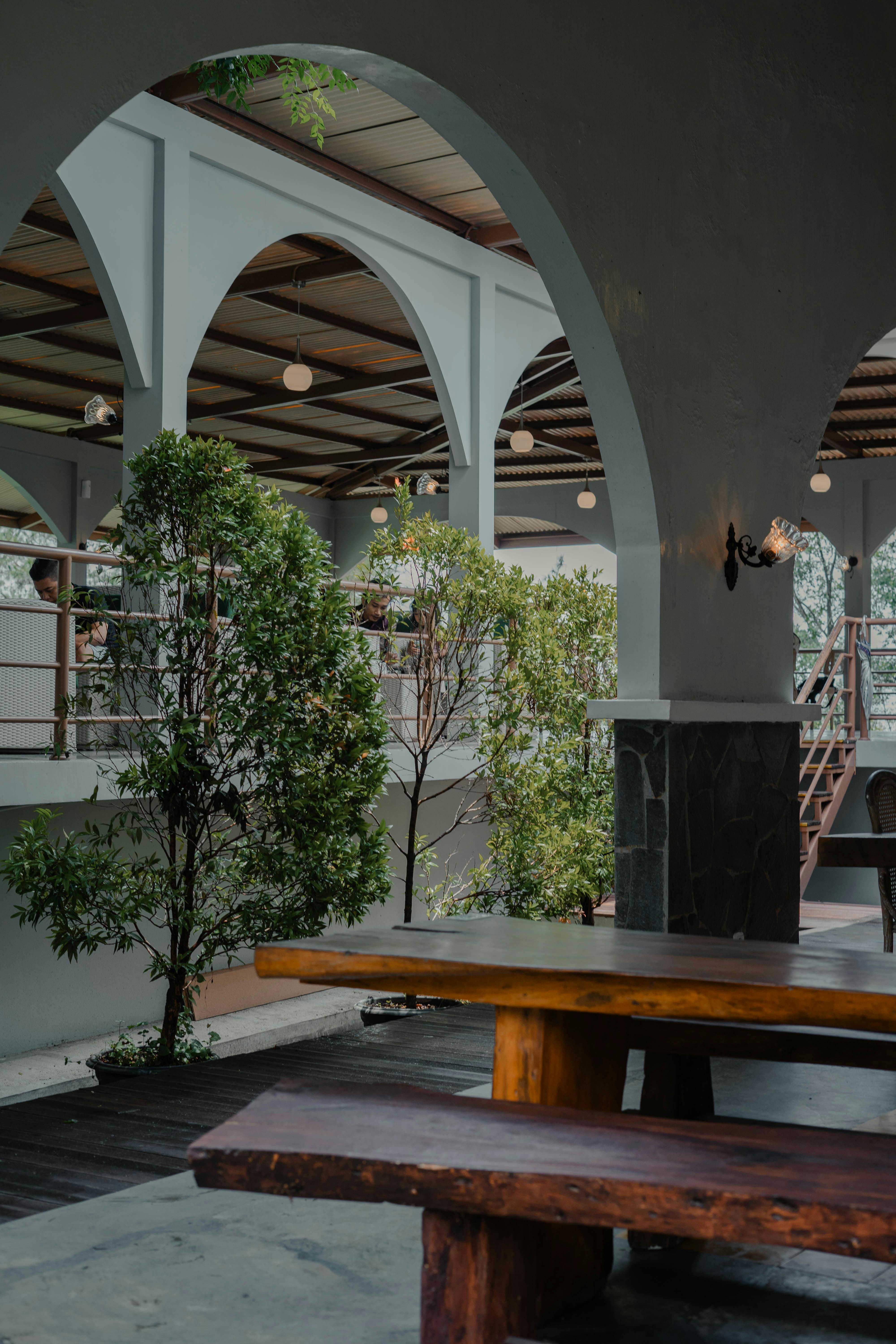 Spacious restaurant interior featuring elegant arches and greenery for a serene dining atmosphere.