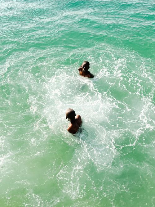 Free Two children swimming in vibrant turquoise ocean waters on a sunny day. Stock Photo