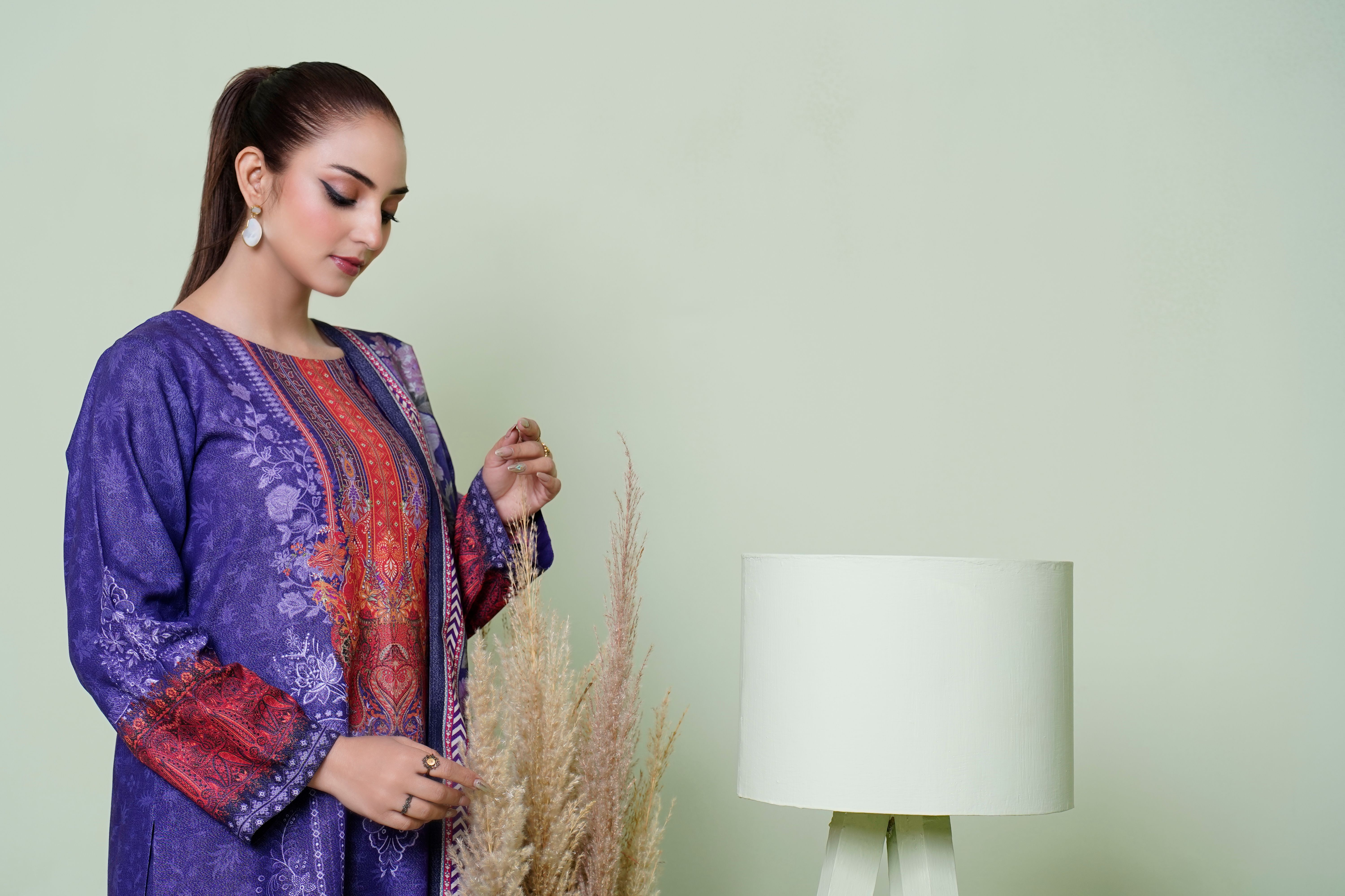 A woman in traditional dress poses in a modern living room setting with a lamp.
