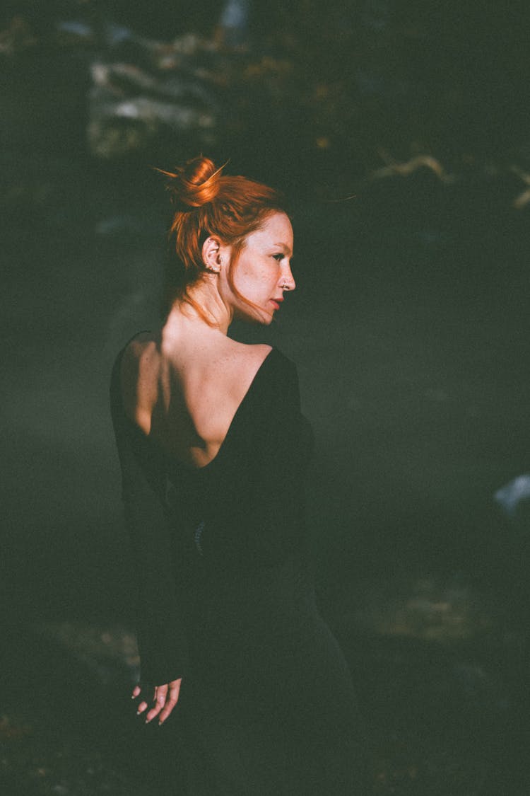 Young Woman In A Black Dress With Open Back Standing Outside 