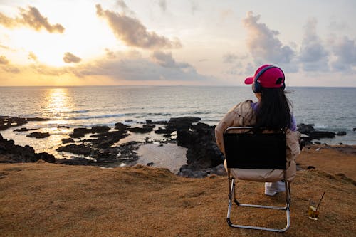 Woman Sitting on Chair on a Shore During Sunset