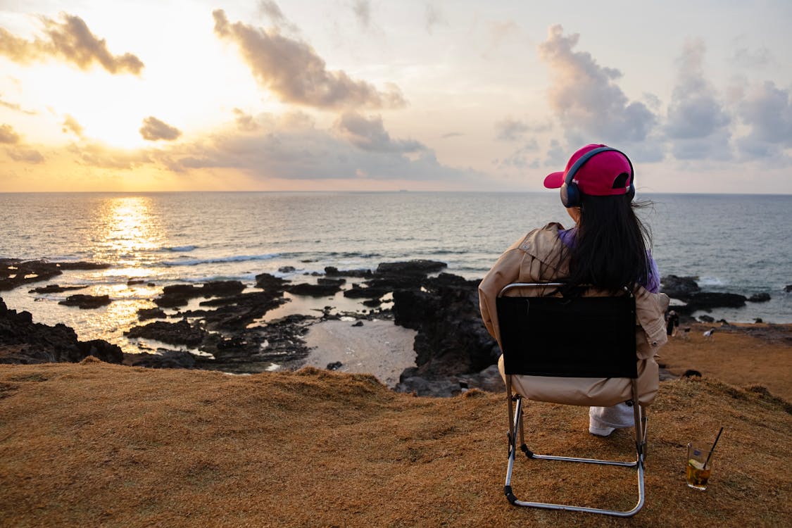 Woman Sitting on Chair on a Shore During Sunset