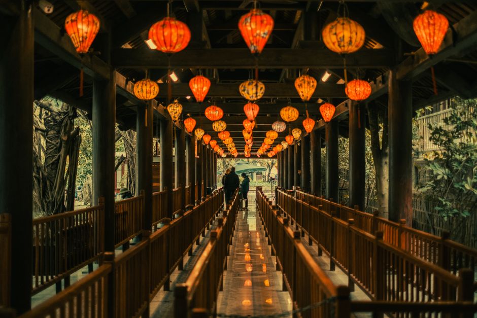 A vibrant display of traditional lanterns illuminating a wooden walkway during the night.