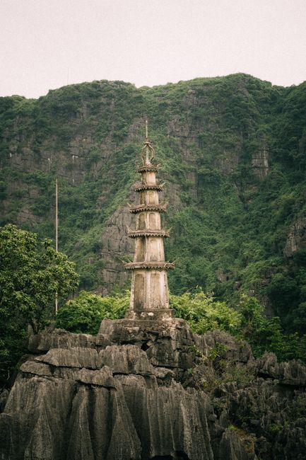 Historic stone pagoda stands majestically among lush green mountains of Ninh Binh, Vietnam.
