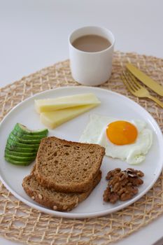 A balanced breakfast featuring avocado, egg, cheese, bread, and coffee.