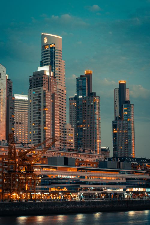 Free A breathtaking view of illuminated skyscrapers at twilight reflecting on waterfront, capturing urban elegance. Stock Photo