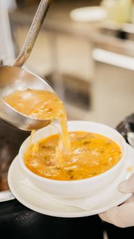 A ladle serving hot Turkish soup into a white bowl, showcasing traditional cuisine in Unye, Turkey.
