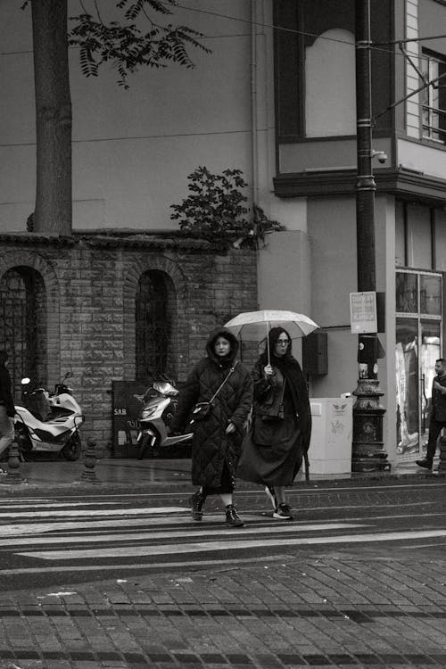 Women Crossing Street in Town in Rain in Black and White
