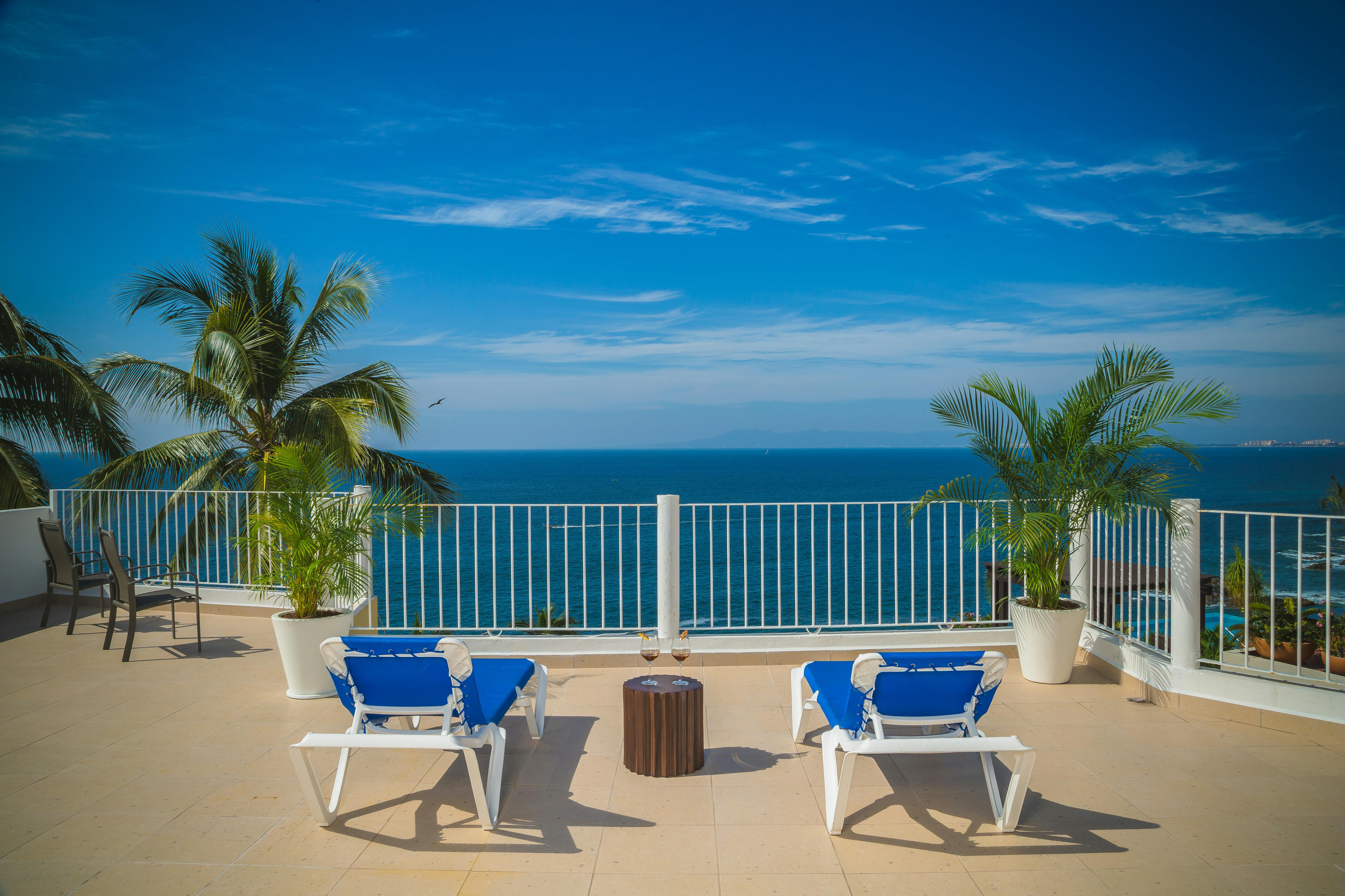 在海滨阳台上，躺在躺椅间，伴着棕榈树，欣赏宁静的海景