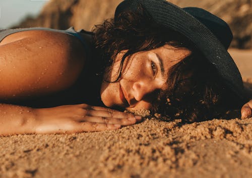 Woman Wearing Hat Lying on a Beach 