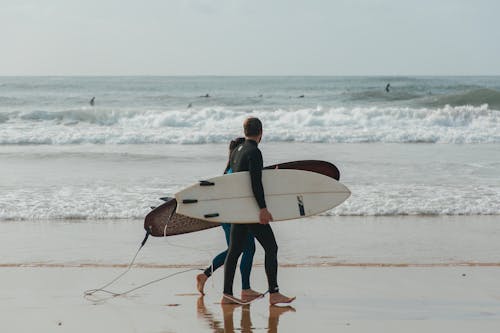 Two Surfers Walking on a Beach